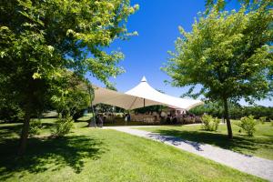 a tent in a park with a group of people under it at Agriturismo Greppi in Crescentino