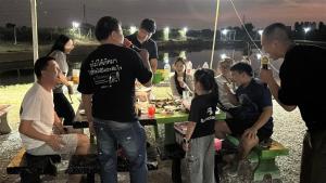 a group of people standing around a table with food at บ้านสวนจุกทิพย์ โฮมสเตย์ in Ban Sam Kaeo