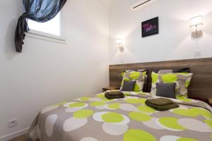een slaapkamer met een groen en wit bed met kussens bij Appartement Des Iles in Juan-les-Pins