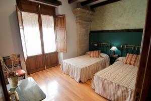 Duas camas num quarto com paredes verdes e pisos em madeira em Vivienda Turística Yamaries em Úbeda