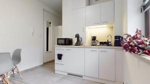 a white kitchen with white cabinets and appliances at Studio Fibra Metrio in Rybnik +11 photos