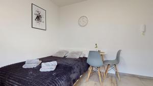 a bedroom with a bed and a table and a clock at Studio Fibra Metrio in Rybnik