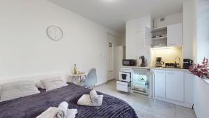 a white bedroom with a bed and a kitchen at Studio Fibra Metrio in Rybnik