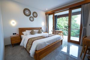 a bedroom with a large bed and a balcony at Sandat Garden House in Ubud