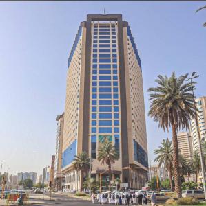 a tall building with people standing in front of it at Elaf Al Sagryah Hotel in Mecca