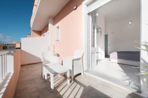 a balcony with white chairs and a bed at B&B a due passi dal centro in Castelsardo