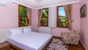 a bedroom with a bed and a chair and windows at Marmaris Holiday Villas in Marmaris