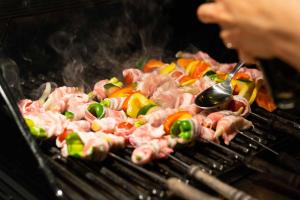 a person cooking meat and vegetables on a grill at Tiny Base in Kawazu