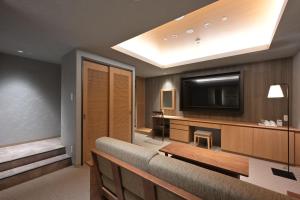 a living room with a couch and a flat screen tv at HOTEL THE7 Kumamoto in Kumamoto