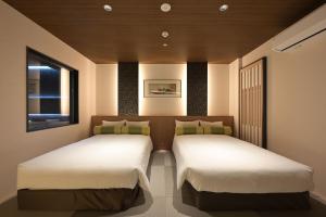two twin beds in a room with a window at HOTEL THE7 Kumamoto in Kumamoto