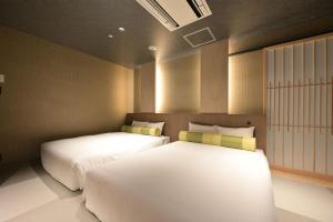 two beds in a small room with twoermottermott at HOTEL THE7 Kumamoto in Kumamoto