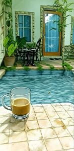a cup of coffee sitting on a table in front of a pool at Regina Cottage in Ngurblut