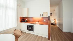 a kitchen with white cabinets and a sink at Strandhotel Domburg - Next Door in Domburg