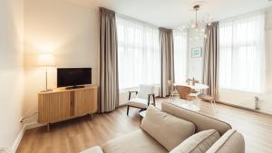 a living room with a couch and a tv at Strandhotel Domburg - Next Door in Domburg