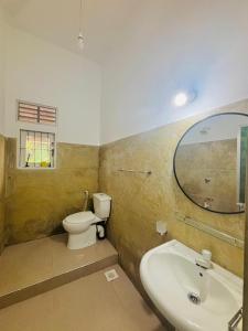 a bathroom with a sink and a toilet and a mirror at HotelSide Residences in Negombo