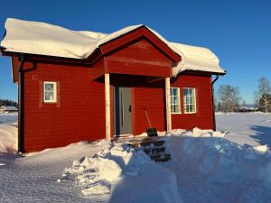 a small red house with snow on the ground at Hjortgården in Mora