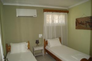 two beds in a small room with a window at Garneli Apartments in Kalami