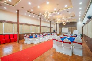 a banquet hall with red and white chairs and a red carpet at Hotel Varun in Guna