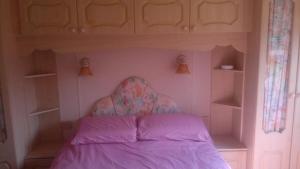 a small bedroom with a bed with purple sheets at Caravan by Sea in Morfa Nefyn