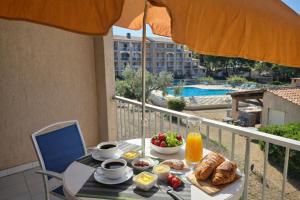 a table with breakfast food on a balcony with an umbrella at Studio cabine Meublé de Tourisme 2 étoiles in Balaruc-les-Bains