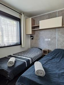 a bedroom with two beds and a window at Mobil home - La carabasse 4 Etoiles - 3 chambres in Vias +11 photos