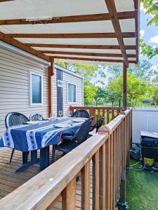 a patio with a table and chairs on a deck at Mobil home - La carabasse 4 Etoiles - 3 chambres in Vias