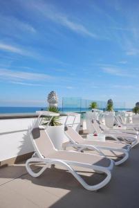 a row of white lounge chairs on a balcony with the ocean at Hotel Imperiale & SPA in Gatteo a Mare