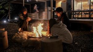 a group of people sitting around a fire at Tiny Base in Kawazu