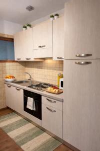 eine Küche mit weißen Schränken und einem Herd mit Backofen in der Unterkunft Chalet Lawà in Torre Caprara
