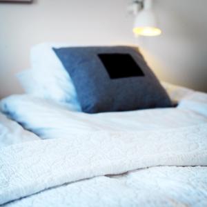 a close up of a white bed with a blue pillow at Våningen vid Havet in Simrishamn +4 photos