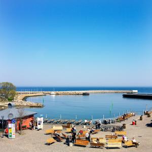 a group of people sitting on benches near a body of water at Våningen vid Havet in Simrishamn