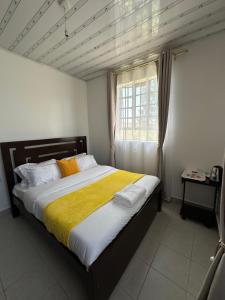 a bedroom with a large bed with a yellow blanket at Rhacky Homes - Near JKIA & SGR in Nairobi