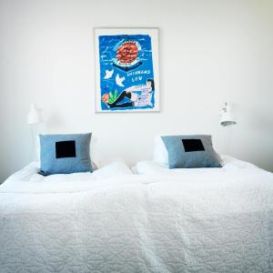 a large bed with white sheets and blue pillows at Våningen vid Havet in Simrishamn