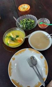a wooden table topped with plates and bowls of food at Sawinsrom Homestay in Fam