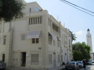 un edificio blanco con coches estacionados frente a él en Maison d'Hôtes Dar Ennassim, en La Marsa