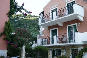 a pink apartment building with balconies and flowers at Garneli Apartments in Kalami