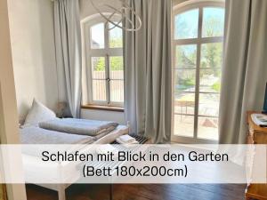 ein Schlafzimmer mit einem Bett und zwei Fenstern in der Unterkunft FeWo "Ebbe" im historischen Denkmal, ruhig & modern mit Stil, Kunst und großem Garten, hochwertiger Ausstattung & zentraler Lage in Esens- 3km zur Nordsee, alles fußläufig erreichbar - ideal für Paare oder kleine Familien in Esens