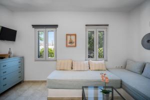 a white living room with a couch and windows at Indigo Studios in Livadi