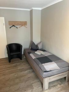 a bedroom with a bed and a black chair at Die Kantine Wittenburg Zimmervermietung und Hostel in Wittenburg