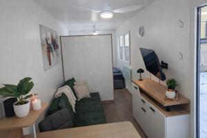 ein Wohnzimmer mit Sofa und Schreibtisch mit Fernseher in der Unterkunft Auszeitbox in Schärding