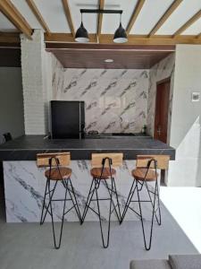 a kitchen with a counter with two stools and a table at Villa Sunyi Lombok in Tanjung