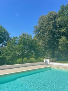 a swimming pool with a chair and some trees at La Joie de Vivre in Bonnefont +24 photos