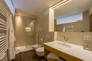 La salle de bains est pourvue d'un lavabo, de toilettes et d'un miroir. dans l'établissement Appartement Hotel Erlhof Deluxe, à Lutago