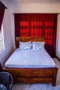 a bedroom with a wooden bed with a red curtain at Osim Bnb in Arusha
