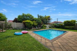 a swimming pool in a yard with two oogie boards at Swallows Rest Cottage KZN in Scottburgh
