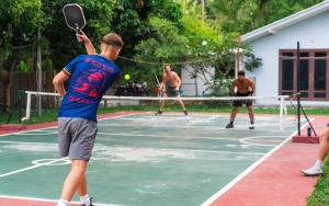 a group of men playing tennis on a tennis court at Tiki Beach Koh Phangan Beach Restaurant Bar and Coworking in Ban Tai