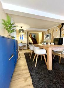 a dining room with a wooden table and white chairs at Autour d'une Toile in Rouvenac