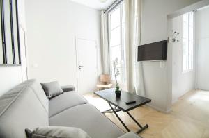 a white living room with a couch and a table at Dreamyflat - Apartment Opera 3 in Paris