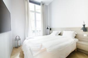 a white bedroom with a large white bed and a window at Dreamyflat - Apartment Opera 2 in Paris
