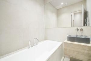 een witte badkamer met een wastafel en een bad bij Dreamyflat - Apartment Opera 2 in Parijs